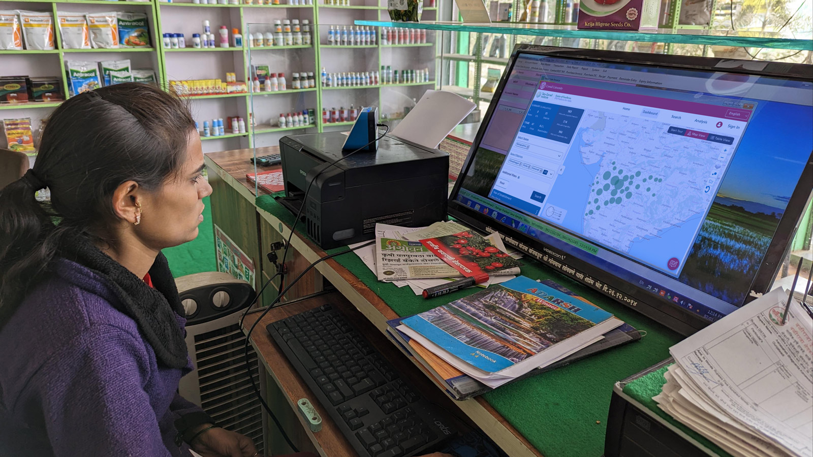 Woman sitting behind a counter of a medical store in India and working on a computer