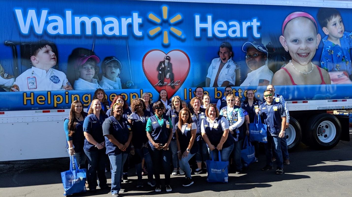 Photo of group of people standing in front of a Walmart Truck with Walmart Heart painted on it.